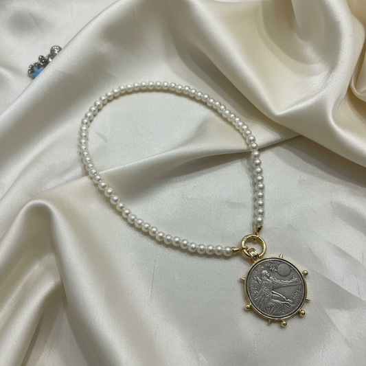 Collar perlas con moneda antigua fondo crema elegante